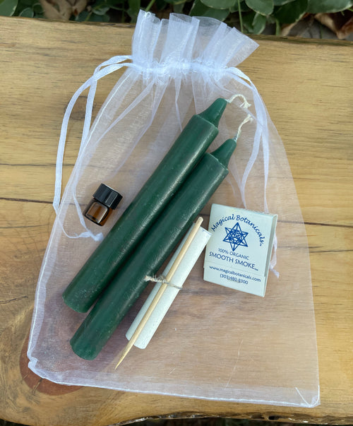 Green candles with a card on a sheer bag on a wooden surface